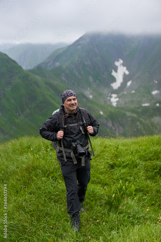 Fototapeta premium Hiker man with backpack on a mountain trail