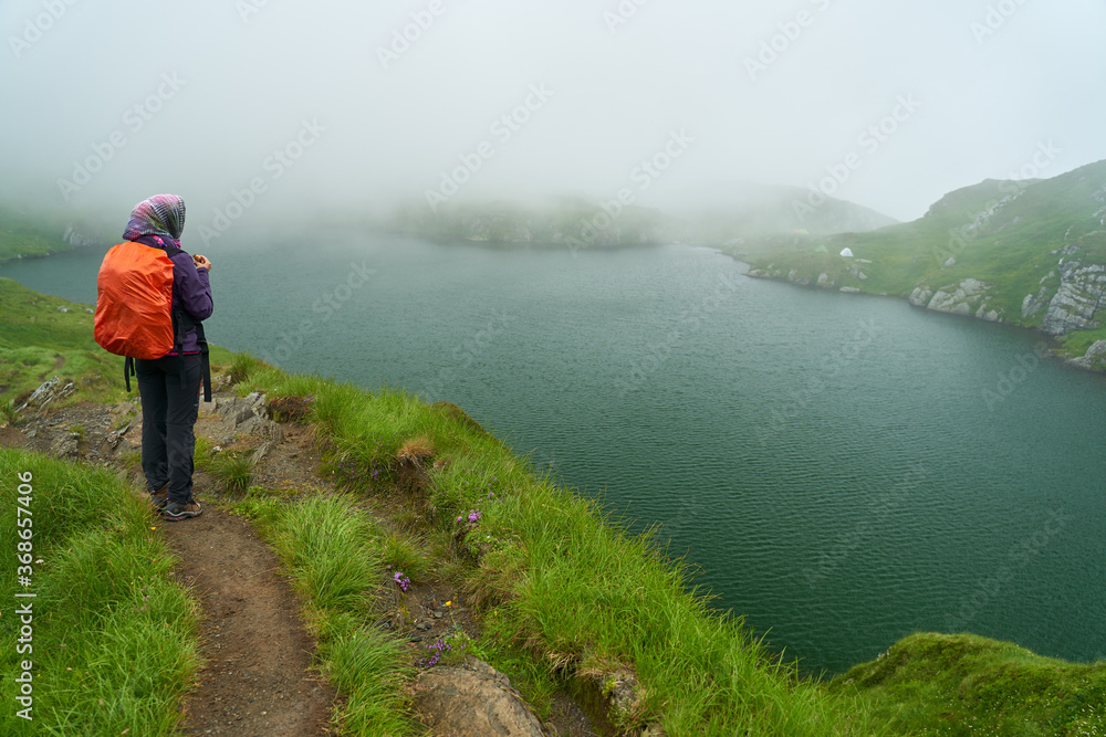 Woman hiking by a lake in the mountains