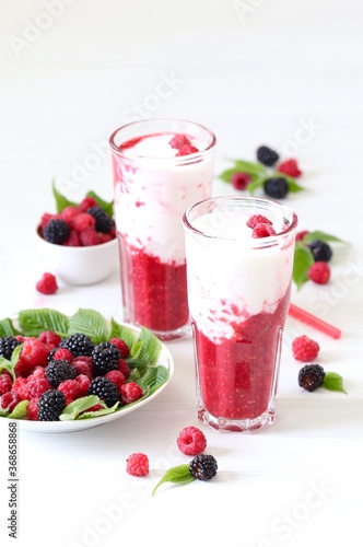 Milk berry refreshing drink  cocktail with ice cream  fresh raspberries and blackberries in a glass on a white background