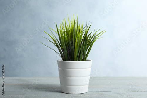 Artificial plant in flower pot on light grey wooden table