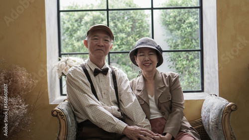 Vintage retro classic dress Asian elder senior couple taking photo at luxury home together