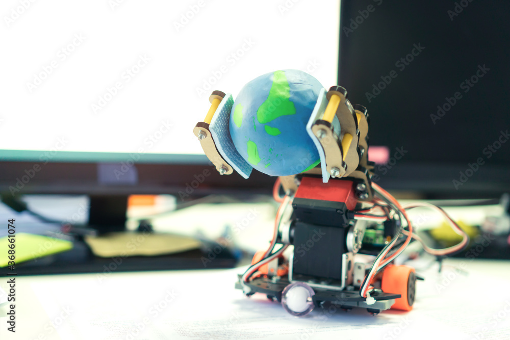 Robotics electronics in laboratory with computer, STEM Education for Learning for student science teachnology on Electronic board. Robot holding model globe by coding programming IOT innovation