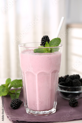 Tasty blackberry milk shake with fresh berries on table