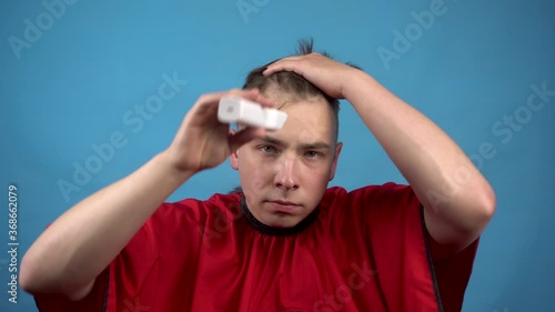 A young man cuts himself baldly. A man uses a hairdressing machine cuts his hair. photo