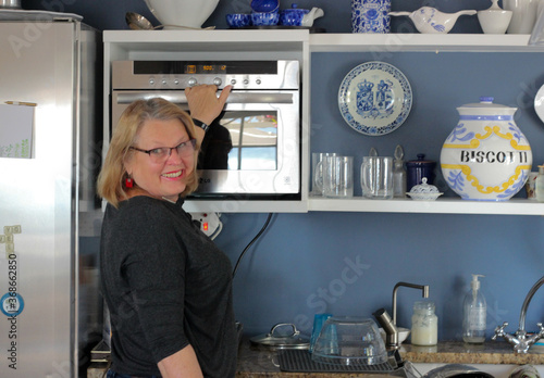 mature woman in kitchen with microwave