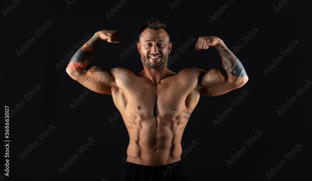 Male bodybuilder on dark background, studio shot Male bodybuilder on dark background, studio shot