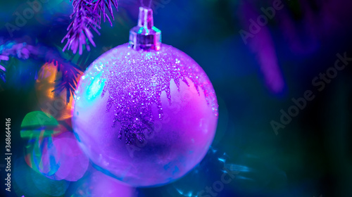 Purple with blue festive Christmas greeting card or invitation. Closeup purple xmas ball with beautiful bokeh on blue background with copy space. Soft focus.