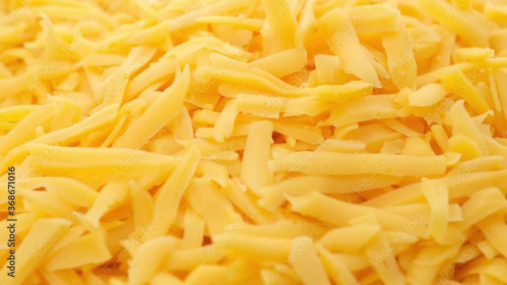 sprinkle grated cheddar cheese close up, rotating sprinkle grated cheddar cheese close up, rotating