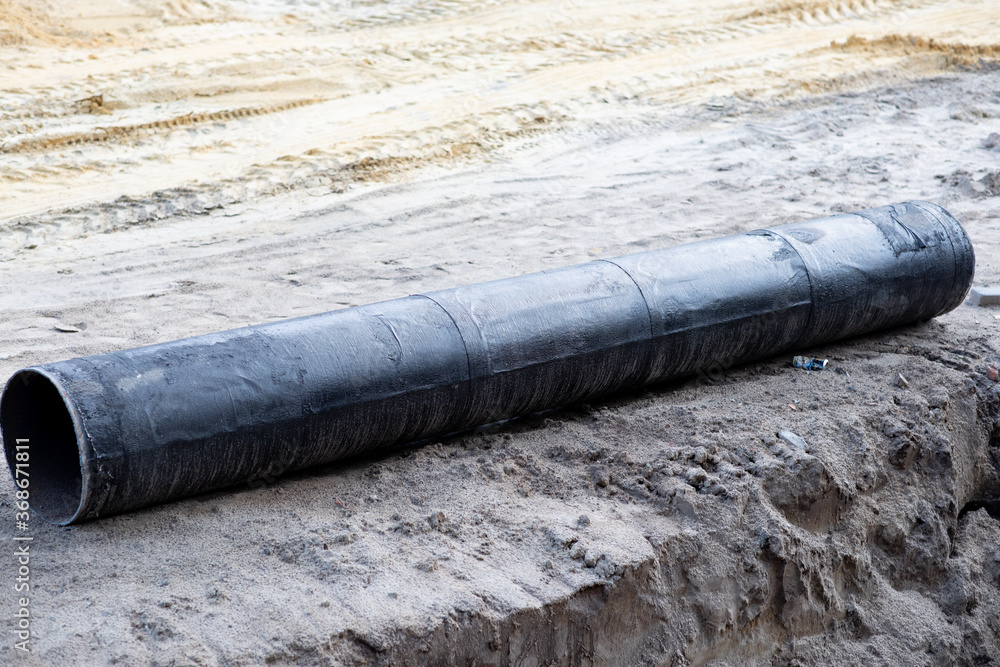 Large black water pipes on the ground at a construction area Large black water pipes on the ground at a construction area