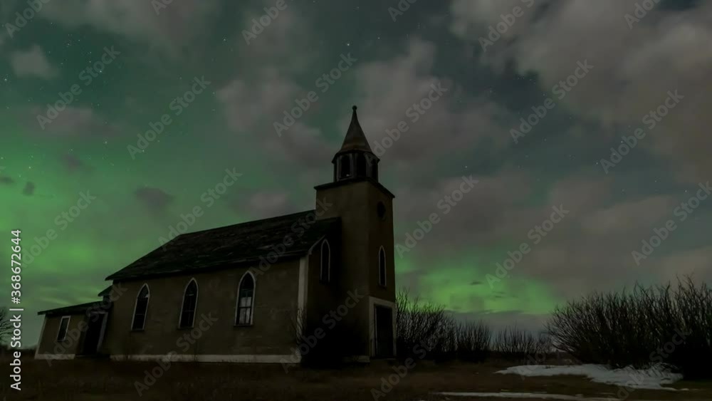 Time lapse of flashing vivid green Northern Lights above an abandoned church with clouds moving through the night sky. Time lapse of flashing vivid green Northern Lights above an abandoned church with clouds moving through the night sky.