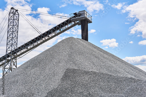 pile of gravel and conveyor belt loader on sky background