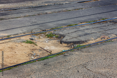 Damaged asphalt road with potholes. Bad road Bad asphalt. Broken road with tram rails, cracks, pits, potholes in the asphalt