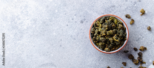 Green tea oolong in a clay tea cup bowl. Grey stone background. Copy space. Top view.