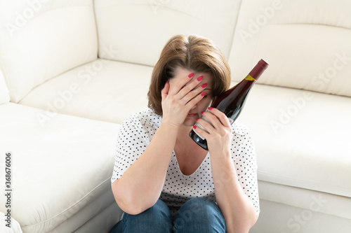 Woman with a headache and a a bottle of wine. Hangover photo