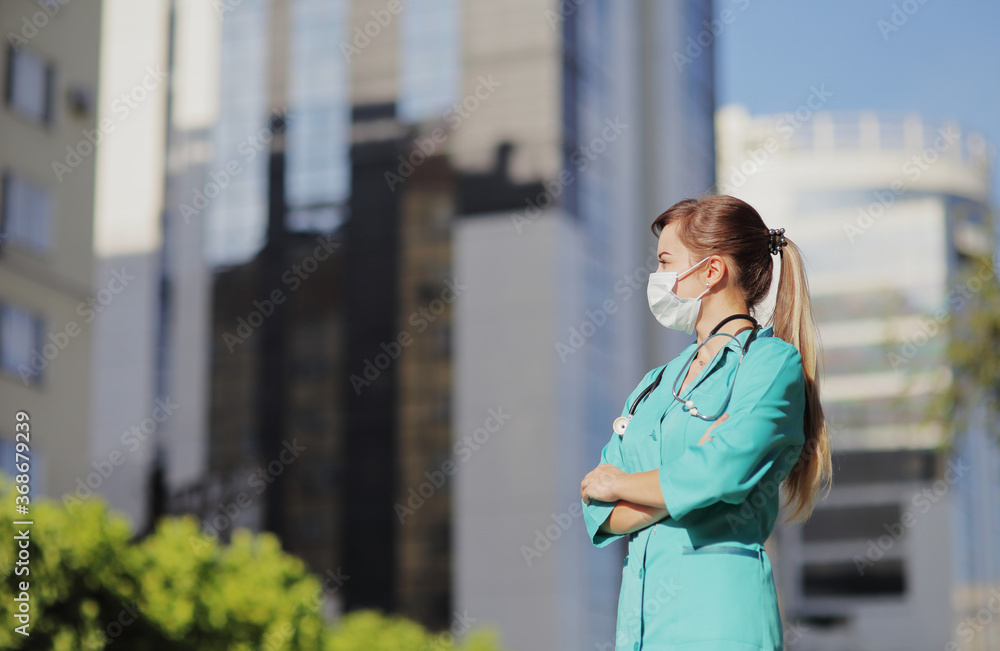 Female doctor, nurse wearing a protective face mask in the city. Skyscraper, sky Female doctor, nurse wearing a protective face mask in the city. Skyscraper, sky