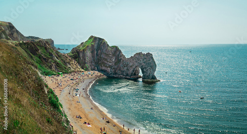Durdle Door, Jurassic Coast near Lulworth in Dorset, England - a natural limestone arch. Durdle Door with people relaxing on the beach on a sunny day in August 2020.