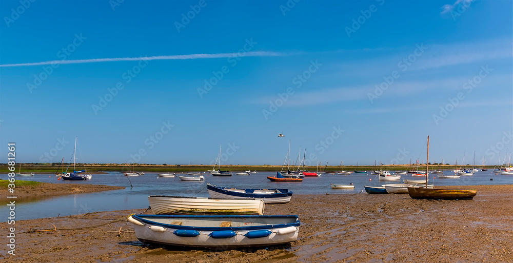 Boats on the shore and moored in Brancaster Bay near Burnham, Norfolk, UK