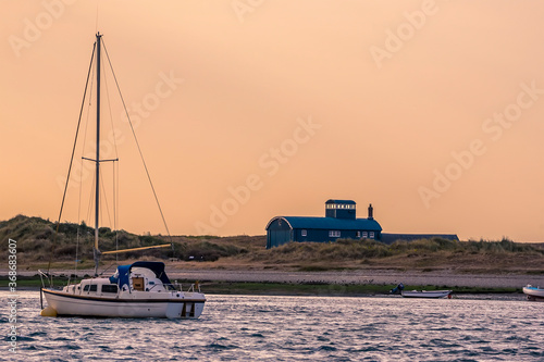 A boat moored at Blakeney Point, Norfolk looking towards the lifeboat station in the distance just before sunset photo