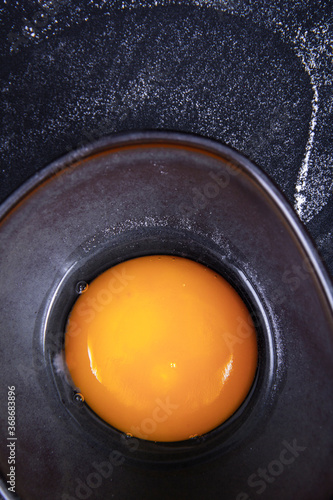 Image of an egg yolk in a bowl with a black background.