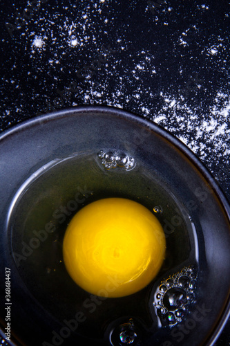 Egg yolk in a dish from a close-up view next to kitchen utensils.