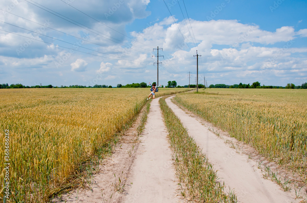 happy girl jump on countryside road. carefree and cheerful woman feel happiness among wheat field. happy about summer vacation. feel the freedom. girl jumping on beautiful landscape of rye field happy girl jump on countryside road. carefree and cheerful woman feel happiness among wheat field. happy about summer vacation. feel the freedom. girl jumping on beautiful landscape of rye field