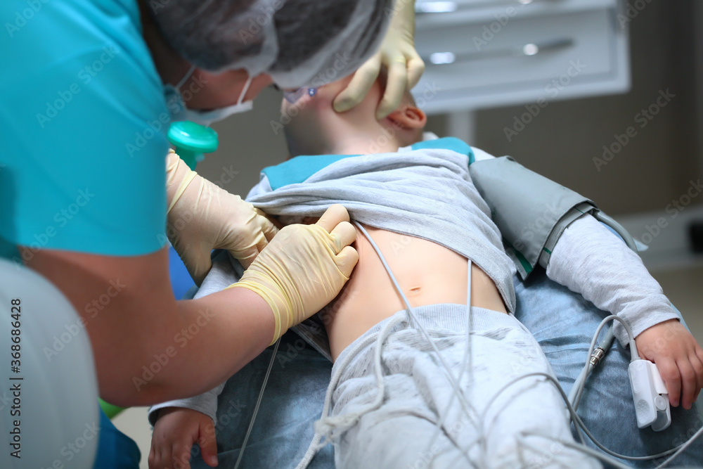 Obraz premium The introduction of a little boy under anesthesia. Preparation for dental surgery to remove multiple caries. Treatment of baby teeth. Copy of the space.