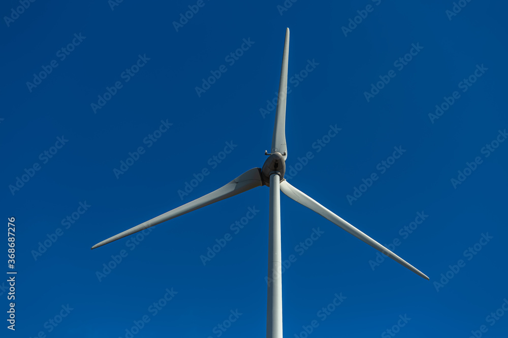 View of a wind turbine on top of mountains, blue sky