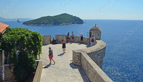 Dubrovnik city wall with tourists and Lokrum island in view.