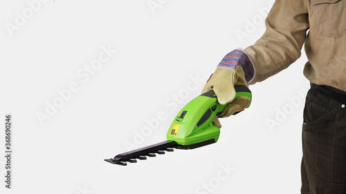 Obraz na plátně Man holds an electric rechargeable garden trimmer to trim hedges and bushes