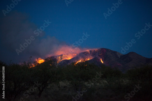 A wildfire burning on the side of a mountain at night