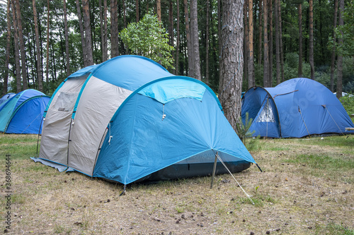 Tourist tents in the forest in a clearing. Summer travel and outdoor recreation. © Anelo