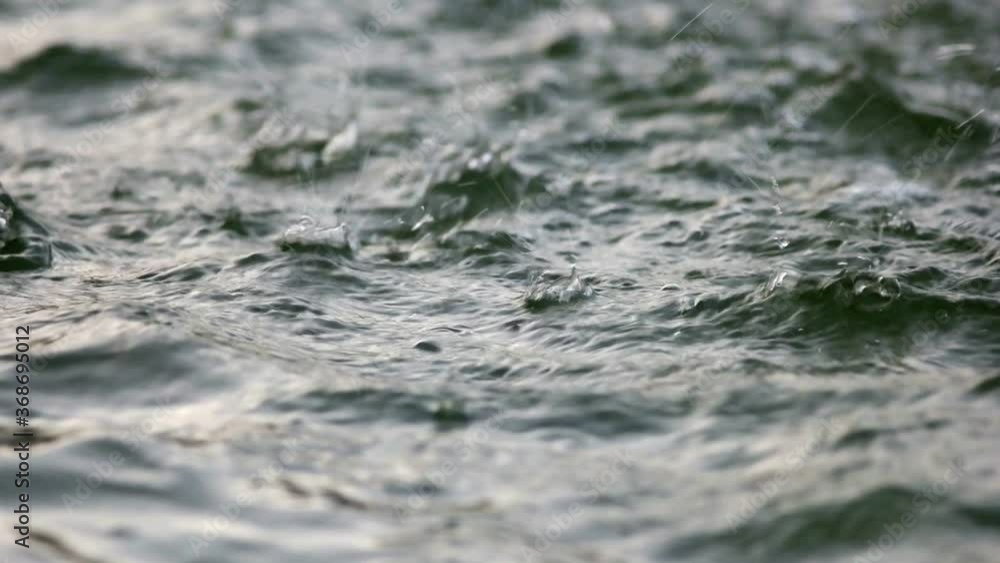 Waves on water surface Disturbing pond surface. Water drops fall from above. Good background for inscriptions. Power of nature. Shallow DOF. Waves on water surface Disturbing pond surface. Water drops fall from above. Good background for inscriptions. Power of nature. Shallow DOF.