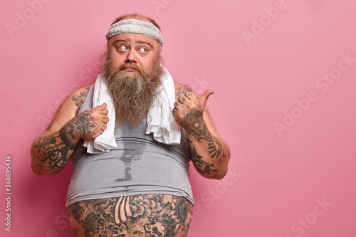 Foto Obese man feels tired and exhausted after cardio training, points thumb aside on