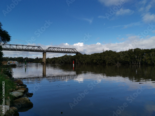 Beautiful view of a river with reflections of tall pedestrian bridge, trees and blue sky, Parramatta river, Rydalmere, New South Wales, Australia