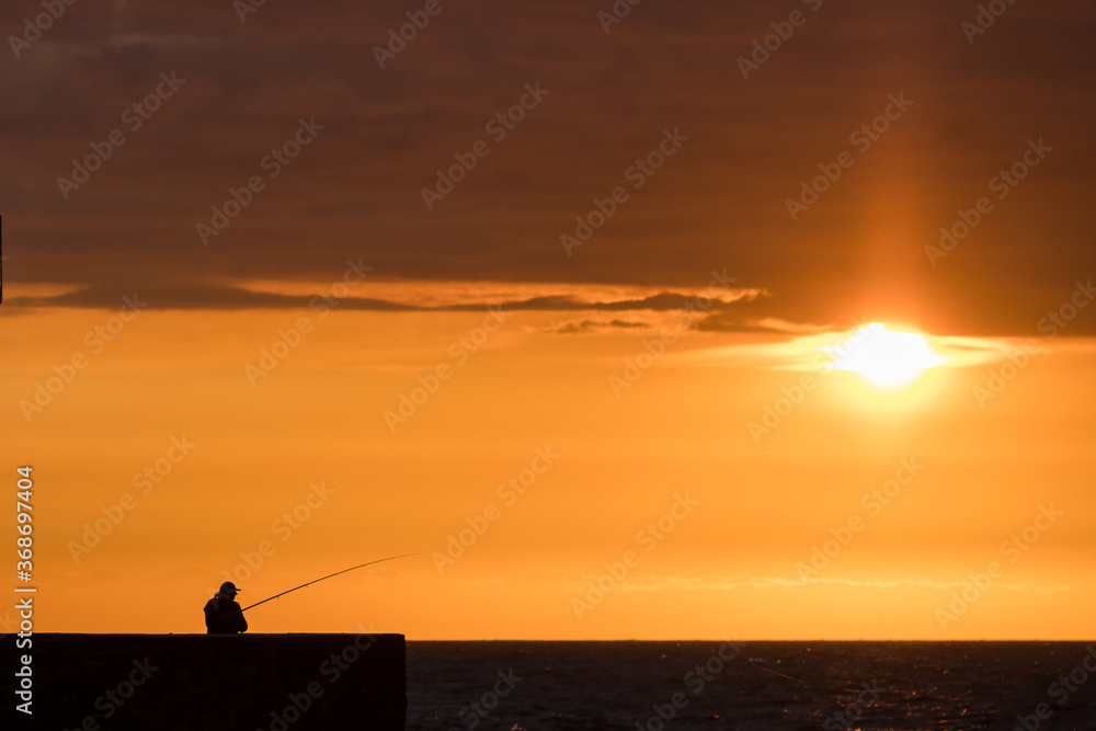 Angler silhouette against the background of a beautiful sunset on the Baltic Sea in Ustka