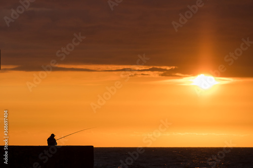 Angler silhouette against the background of a beautiful sunset on the Baltic Sea in Ustka © Konrad