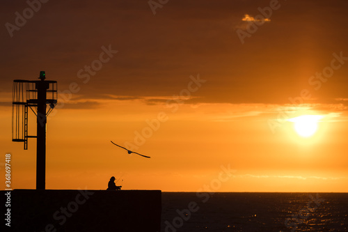 Angler silhouette against the backdrop of a beautiful sunset over the Baltic Sea in Ustka.