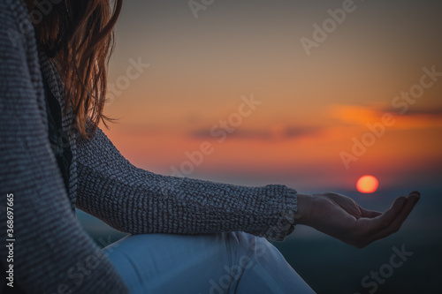 silhouette of a woman holding her hands against the setting sun