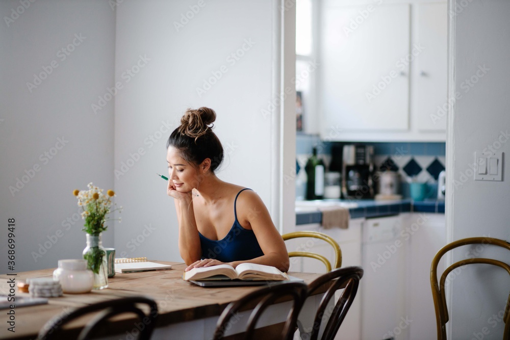Young Asian woman working from home on kitchen dining table Young Asian woman working from home on kitchen dining table