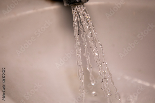 Water Dripping out as wastage during morning routine in wash basin drainage hole with macro shot of water drops showing clear drops to maintain cleanliness in corona
