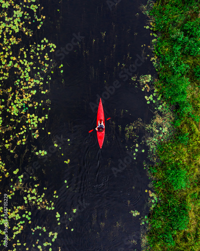 Aerial view of young man paddling in river with red kayak, shot in Lithuania. photo