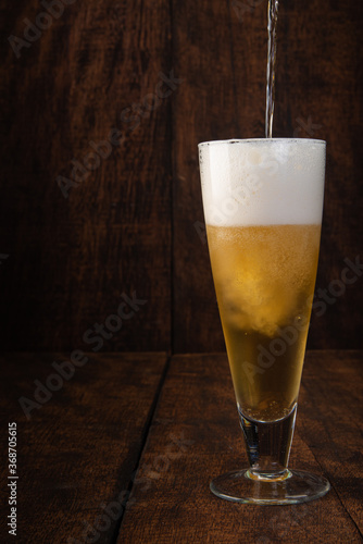 Beer served in a glass with rustic wood background.