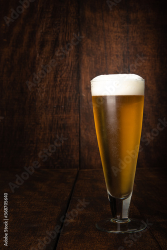 Beer served in a glass with rustic wood background.