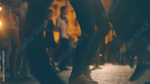 Open-air music festival. Blurred Young people enjoy open-air salsa dancing outside in the street. Blurred Ground level shot of young people dancing salsa on open air event. Many young couples dance