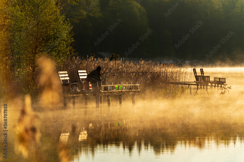 Male fishing on the lake during summer sunrise morning