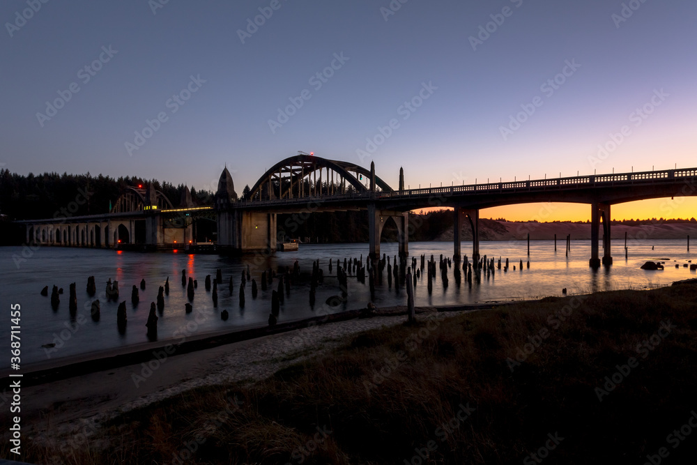 Beautiful historic Siuslaw river bridge in Florence, Oregon, in dusk. Sunset glow reflects in water