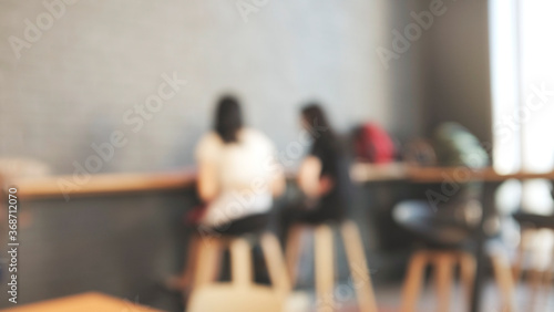 Blurred background image of modern coffee shop. abstract blur background with people in cafe. warm color tone style.