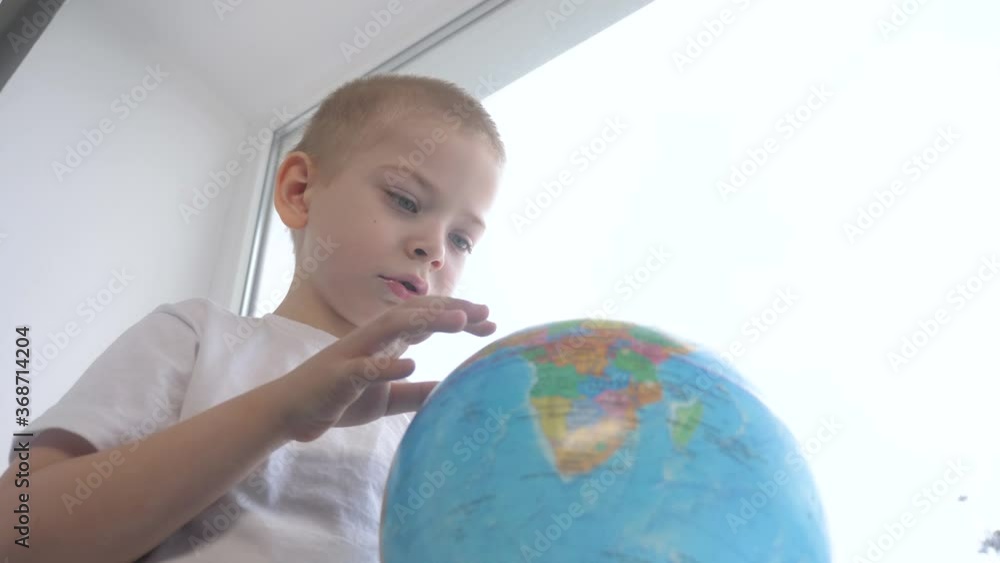 boy studies globe. education travel tourism concept. kid twists lifestyle the globe sits on a window sill. child looking for a country on a globe map . world map geography study boy studies globe. education travel tourism concept. kid twists lifestyle the globe sits on a window sill. child looking for a country on a globe map . world map geography study