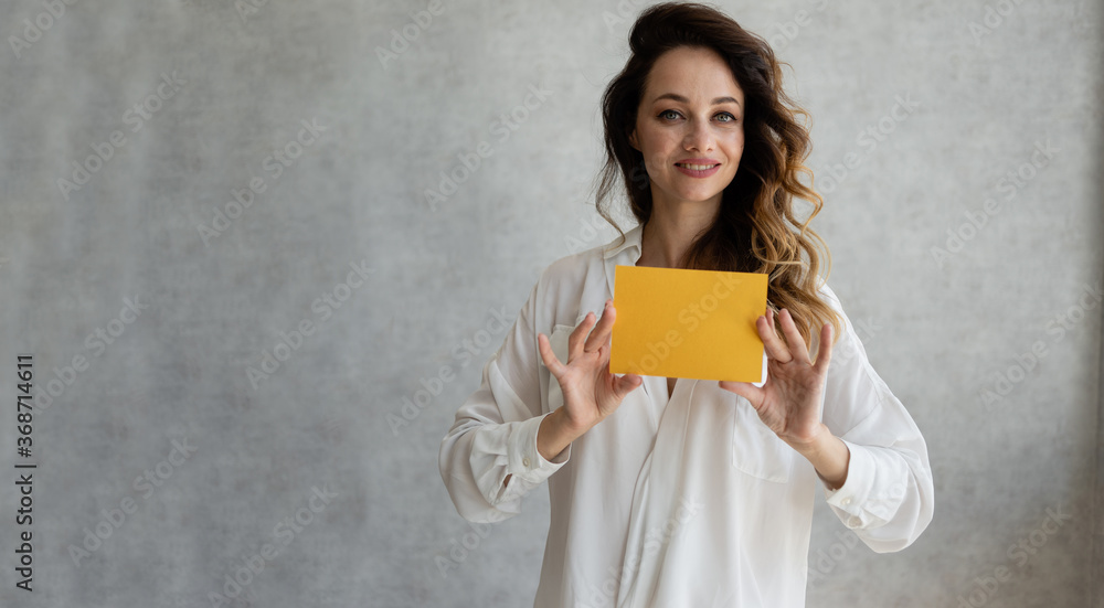 woman holding paper in her hands. Model of the Caucasian race, isolated on a gray background with a leaf in her hands. Horizontal image. woman holding paper in her hands. Model of the Caucasian race, isolated on a gray background with a leaf in her hands. Horizontal image.
