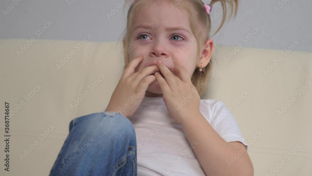 little girl a crying upset tears sitting on the couch. domestic violence concept. unhappy sad girl flow tears lifestyle portrait . upset girl kid cry selected toy little girl a crying upset tears sitting on the couch. domestic violence concept. unhappy sad girl flow tears lifestyle portrait . upset girl kid cry selected toy